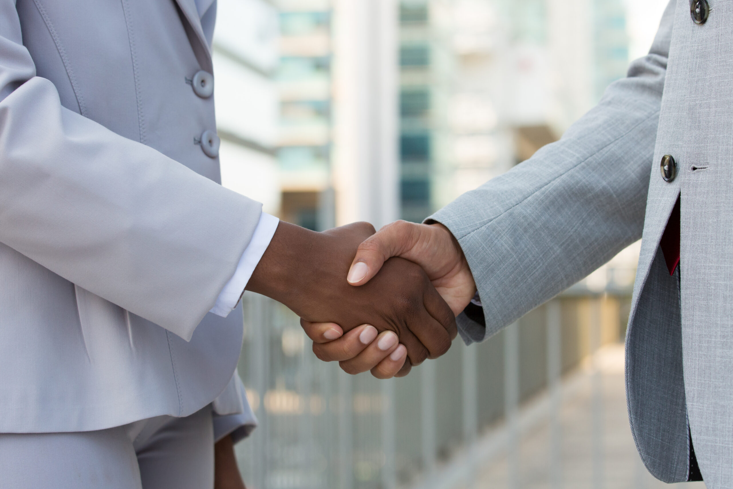 Multiethnic leaders greeting each other in city. Closeup of business man and woman shaking hands outside. Cooperation concept